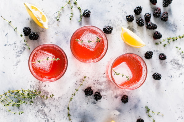 Birds eye view of three red cocktails with blackberries scattered around