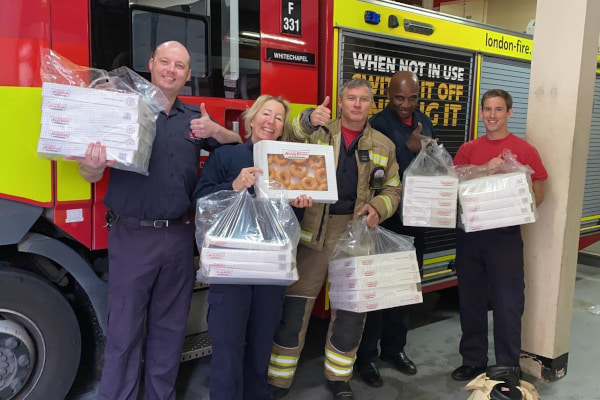 Firefighters in front of truck holding bags of doughnuts