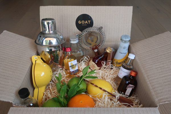 Cocktail making kit ingredients and tools in a cardboard box