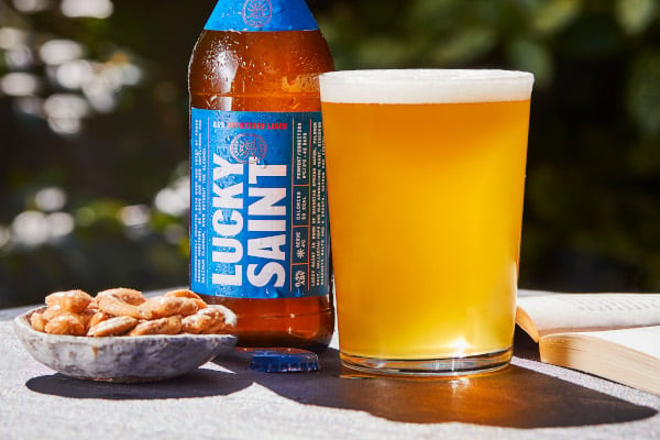 Lucky Saint bottle next to full pint glass and roasted peanuts