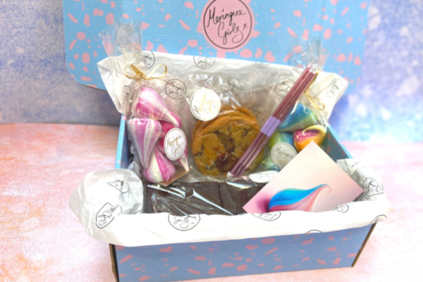 Pastel coloured box filled with cookies, brownies, meringues, and candles