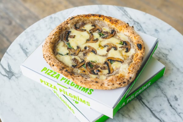White pizza with mushrooms on top of two branded pizza boxes