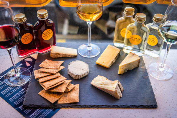 Cheeses on a slate board with bottles of wine